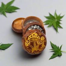 Load image into Gallery viewer, Small 4 part Herb Grinder with Kief catcher. Hand painted gold mushrooms on imitation wood. Sharp teeth, magnetic closure with smooth grinding
