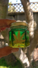Load image into Gallery viewer, Hand Stained-Painted glass nug jar- yellow fading to green( ombre) with a pot leaf painted on top in gold paint.

